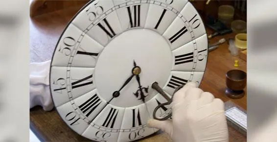Gros plan sur les mains de Jean-Louis Duverger restaurant un cadran d'horloge ancienne